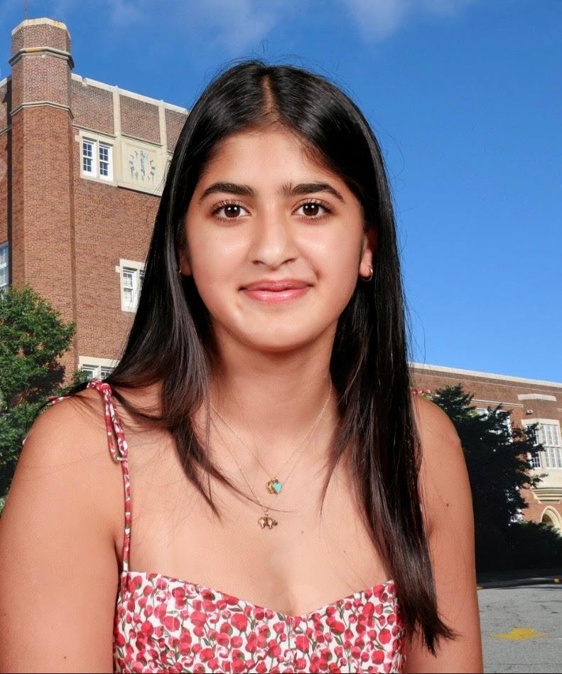 Krisha Wadhwa smiling outdoors in front of a brick school building